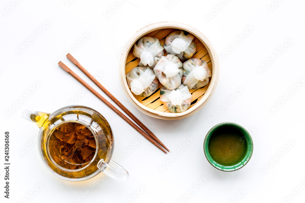 Dim sums with sticks and herbal tea in Chinese restaurant on white background top view