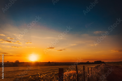 Fototapeta Naklejka Na Ścianę i Meble -  Dramatic Natural Sunset Sunrise Over farm field. Countryside Landscape Under Scenic Colorful Sky At Sundown.