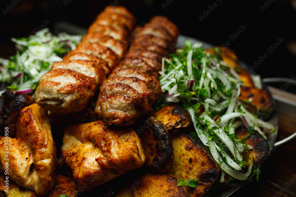 Shish kebab, kebab on a dark background. Different fried meat in plate Shish kebab, kebab on a dark background. Different fried meat in plate