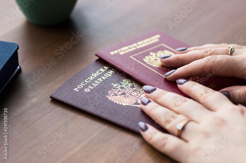 Travel, working, holiday, business concept. A woman holding a Russian passport on the wooden background. People is planning trip or vacation. Close up of woman's hands.
