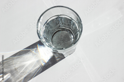 Water glass with strong shadows on white background