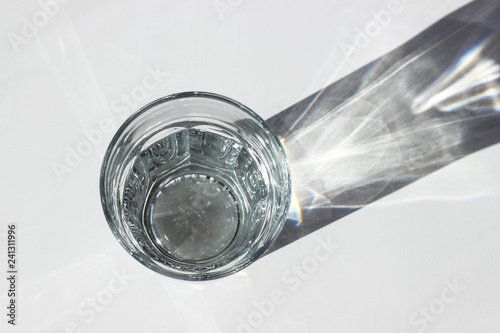 Water glass with strong shadows on white background