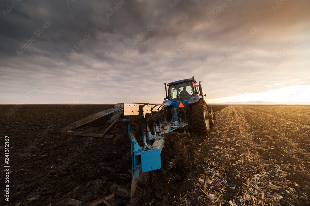 Fototapeta premium Tractor Plowing in dusk