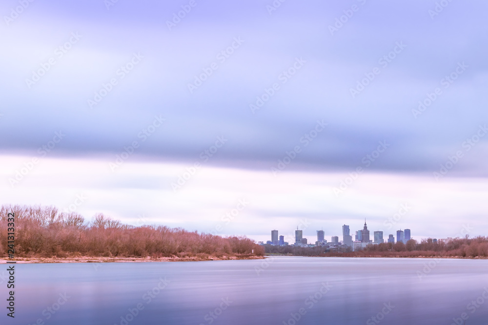 Peaceful Warsaw skyline with view of the skyscrapers in the downtown at the end of the shorlines of the Vistula River in pastel colors