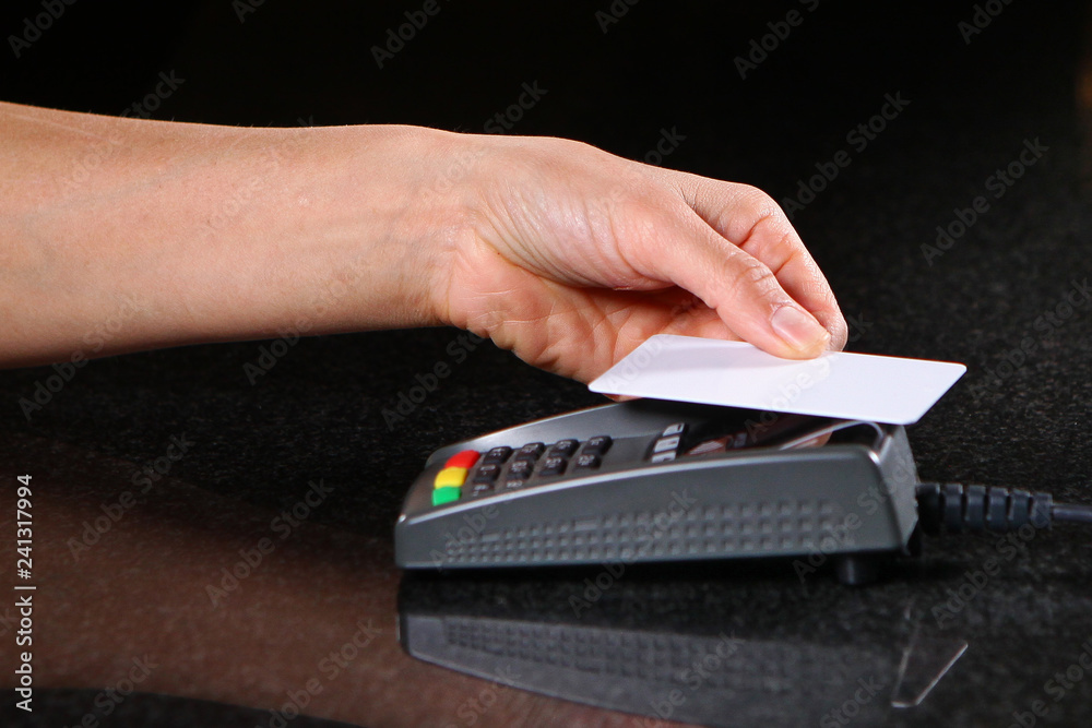 Payment by credit card. Payment through the terminal in a restaurant, shop. Female hand close-up with credit card.