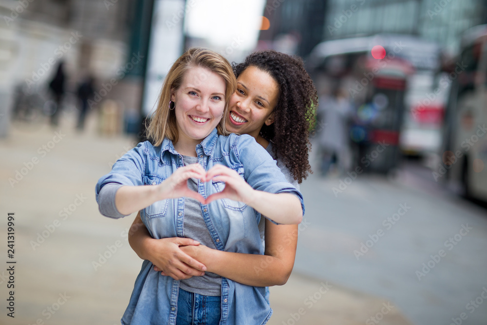 lesbian couple showing a heart shape symbol with their hands lesbian couple showing a heart shape symbol with their hands