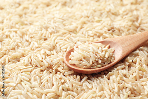 Wooden spoon with raw brown rice on cereal, closeup view