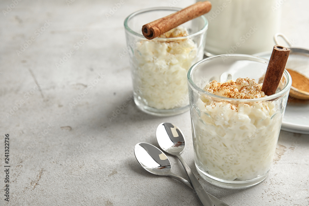 Creamy rice pudding with cinnamon in glasses served on grey table. Space for text Creamy rice pudding with cinnamon in glasses served on grey table. Space for text