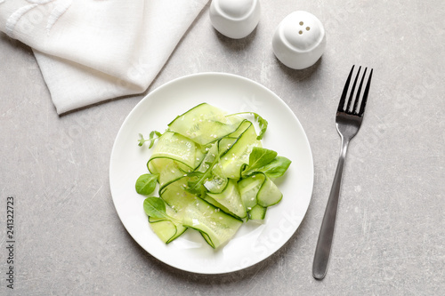 Plate with delicious cucumber salad served on grey table, top view