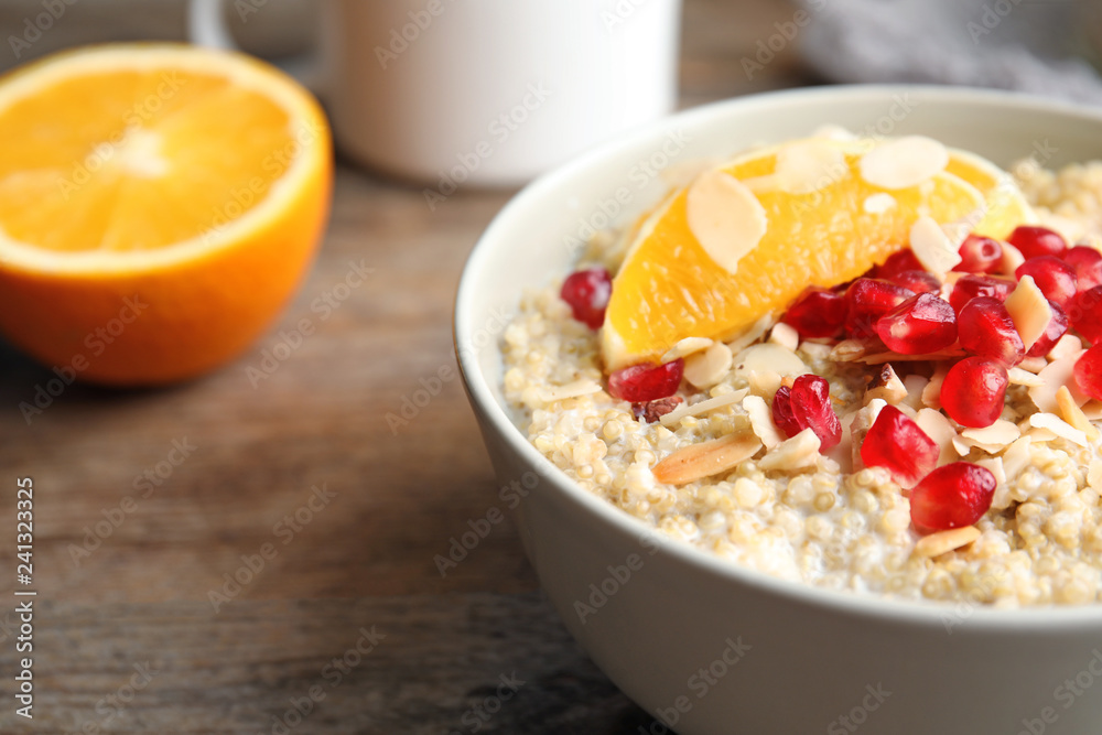 Bowl of quinoa porridge with nuts, orange and pomegranate seeds on wooden table, closeup Bowl of quinoa porridge with nuts, orange and pomegranate seeds on wooden table, closeup