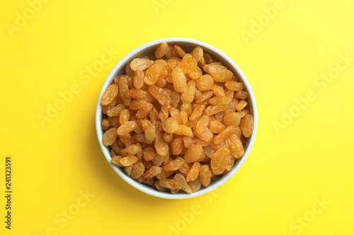 Bowl with raisins on color background, top view. Dried fruit as healthy snack