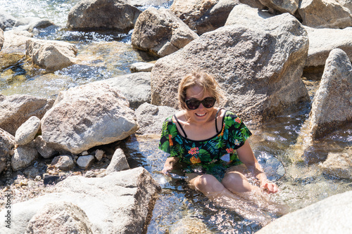 Happy woman wearing a swimsuit sitting in Sacajawea Hot Springs in Idaho, a natural hot springs near a river photo