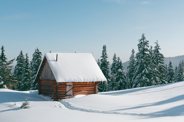 Fantastic winter landscape with wooden house in snowy mountains. Christmas holiday concept. Carpathians mountain, Ukraine, Europe