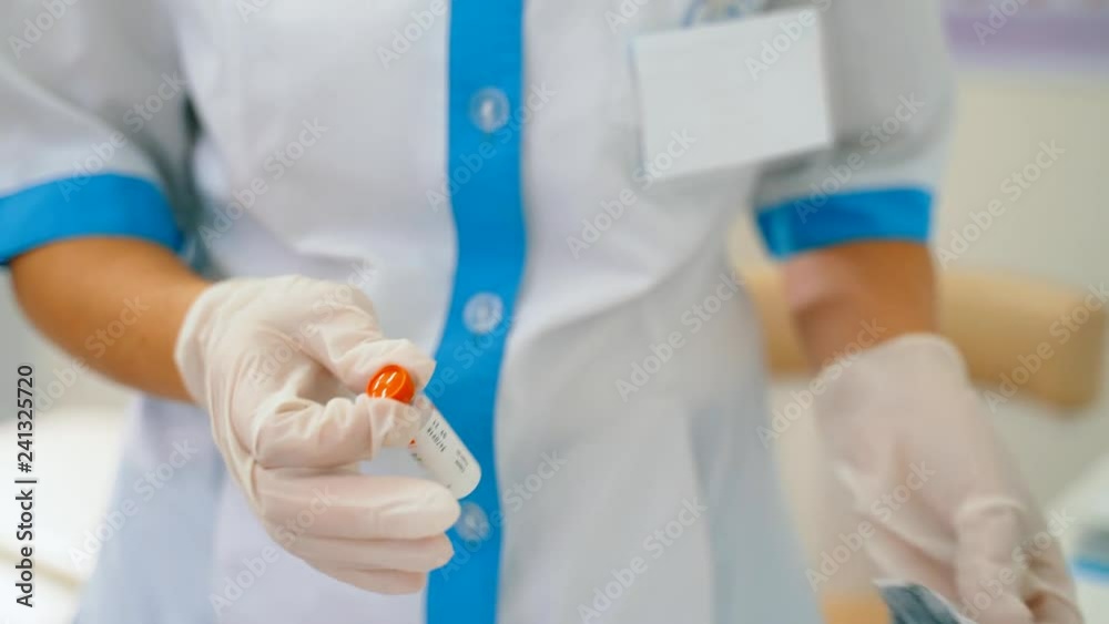 The medical worker takes the bottle out of the package. The drug in the vial. The medical worker takes the bottle out of the package. The drug in the vial.