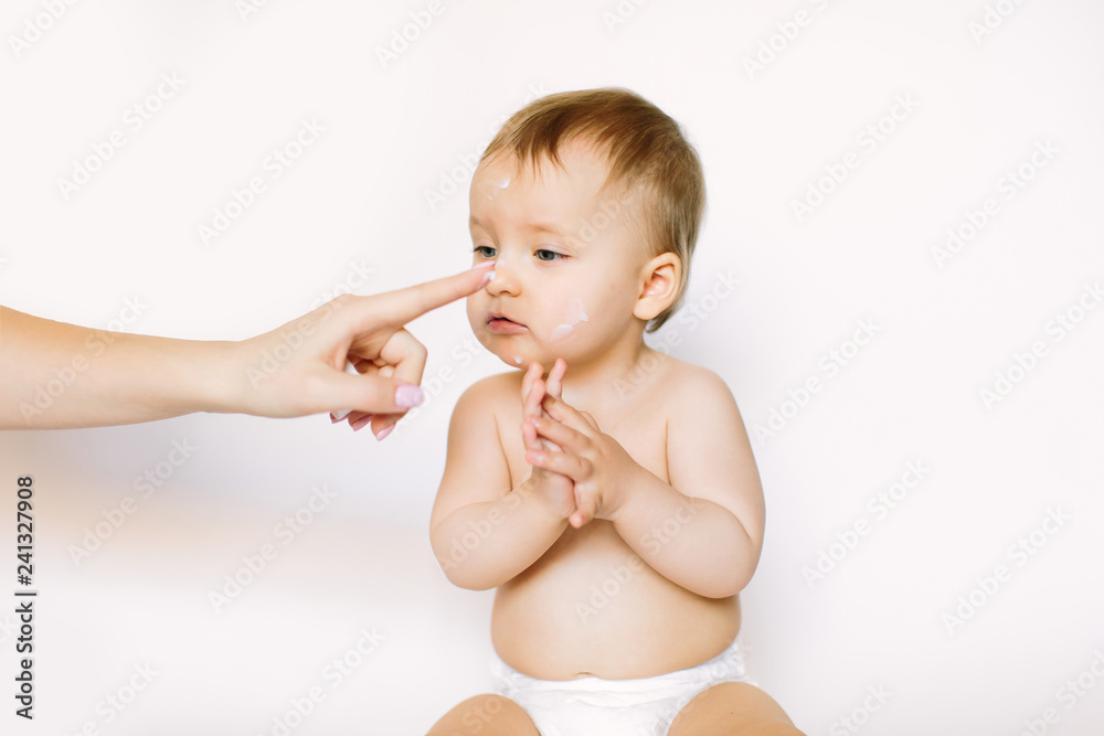 Baby handling: Woman applying moisturizing cream on her baby's face Baby handling: Woman applying moisturizing cream on her baby's face