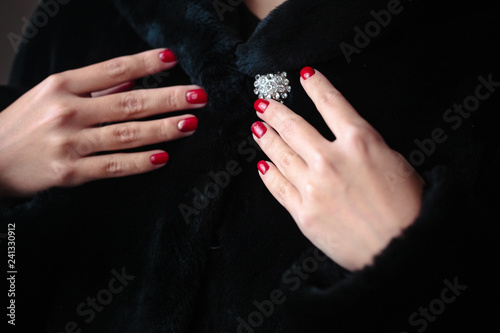 Gorgeous manicure, clssic red color nail polish, closeup photo. Female hands over dark fur background photo