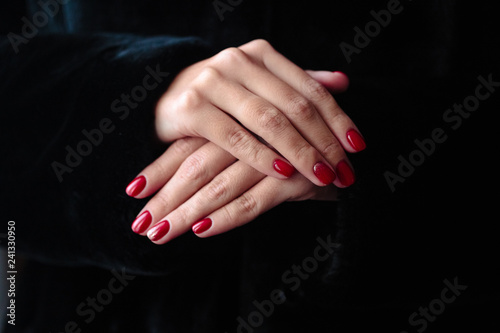 Gorgeous manicure, clssic red color nail polish, closeup photo. Female hands over dark fur background © cherry_d