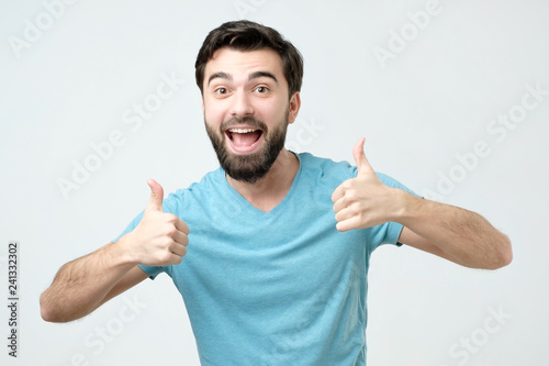 Smiling man showing both thumbs up and looking at camera. Handsome guy advertising something