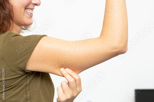 Woman squeezing cellulite on her upperarm photo