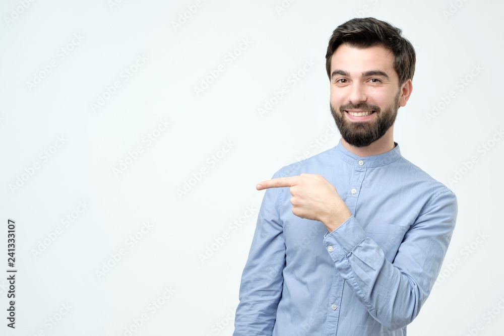 Stylish handsome young hispanic man pointing aside.