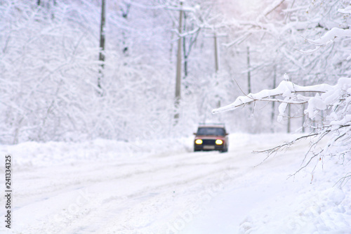 Deep winter scene on a country frozen road with car. Blurred background.