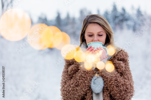 Foto Beautiful girl in coat with cup of hot drink in a snow forest
