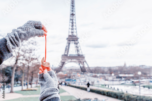 Woman holding little ceramic bird on the Eiffel Tower background. Paris, France