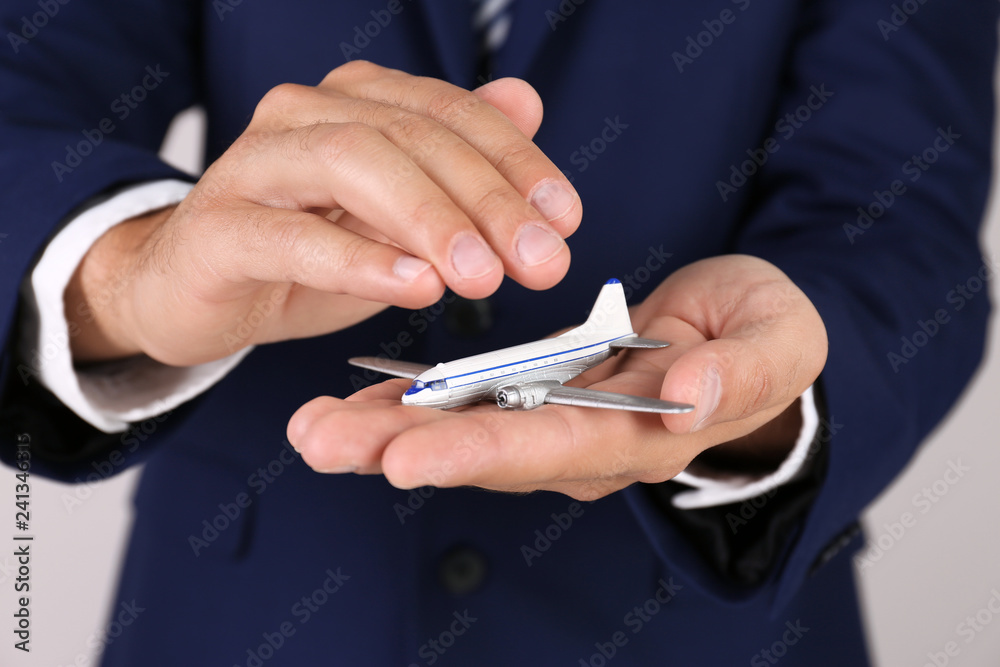 Insurance agent covering toy plane on grey background, closeup. Travel safety concept Insurance agent covering toy plane on grey background, closeup. Travel safety concept