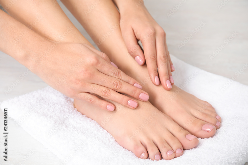 Woman touching her smooth feet on white towel, closeup. Spa treatment