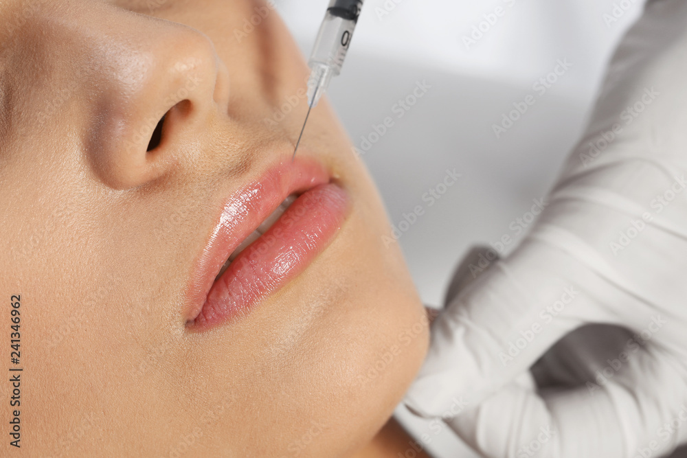 Young woman getting lips injection in clinic, closeup. Cosmetic surgery