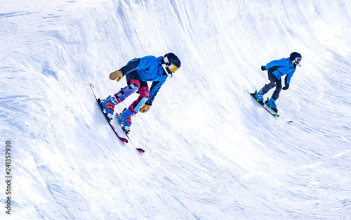 People are enjoying half-pipe skiing / snowboarding 