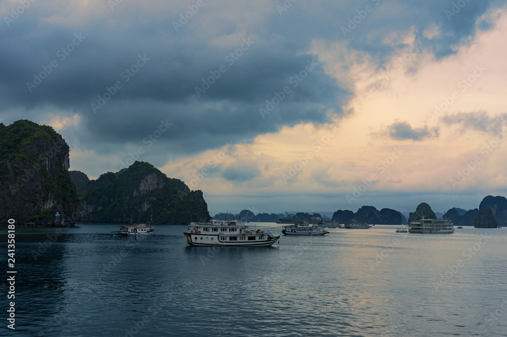Sunset over Ha Long Bay with cruise boats on the water