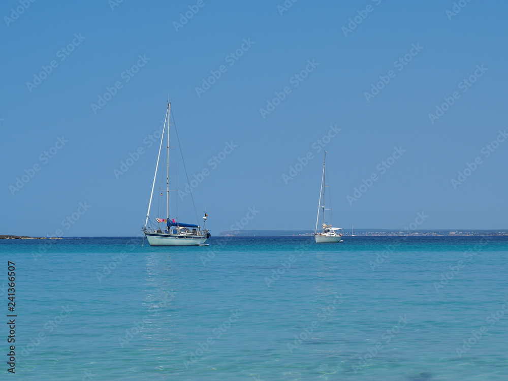 Colonia Sant Jordi, Ses Salines, Spain. Amazing view of the boats with a turquoise sea close to the charming beach of Es Trencs. It has earned the reputation of Caribbean beach of Mallorca