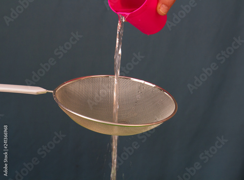 Water poured through a sieve from a pink mag isolated on a clear background image with copy space in landscape format photo