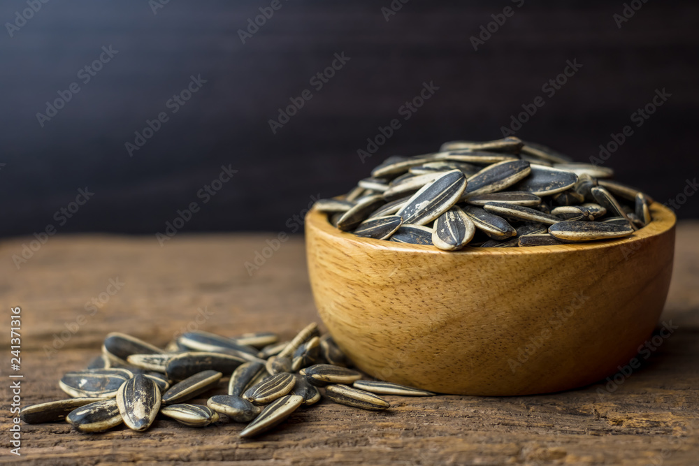 sunflower seeds group with a wooden cup on wood background. The name of science : Helianthus annuus sunflower seeds group with a wooden cup on wood background. The name of science : Helianthus annuus