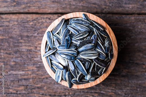 sunflower seeds group with a wooden cup top view on wood background. The name of science : Helianthus annuus.