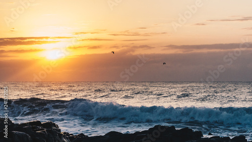 sunrise over the indian ocean with waves and rocks 