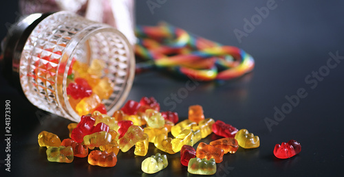 Marmalade in a vase on the table. Sweets in a bowl on a black background. Multicolored jelly sweets for children.