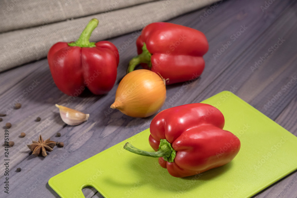 Three sweet red peppers with onion on the table. Process of cooking. Three sweet red peppers with onion on the table. Process of cooking.