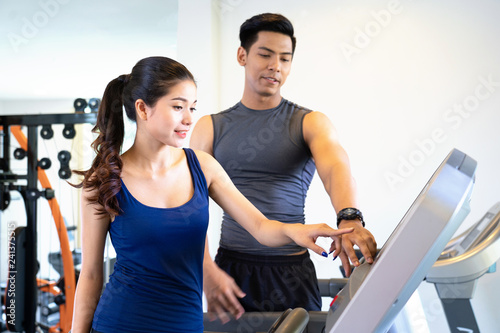 Serious coach giving instruction to a female athlete standing on a treadmill in a fitness centre