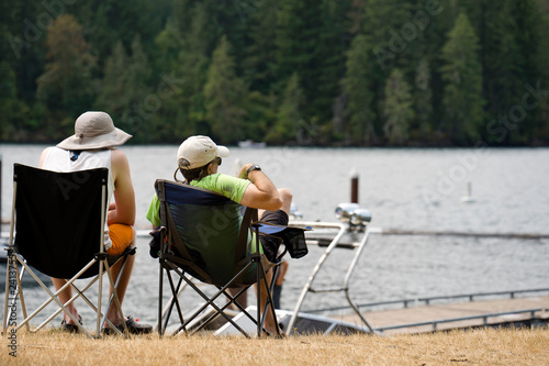Two friends are relaxing on the shore of mountain lake in the forest