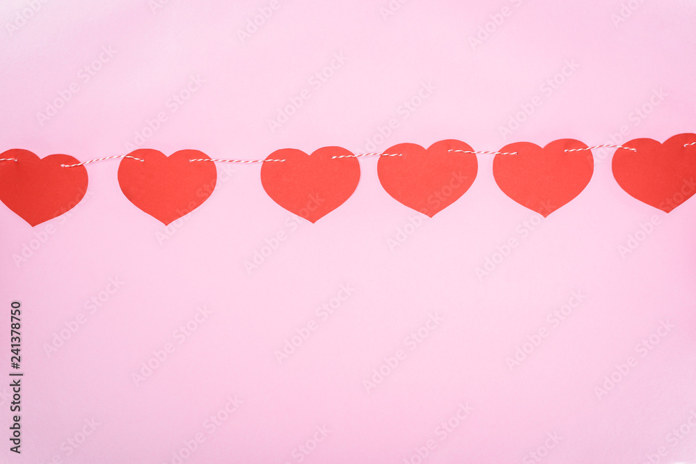 beautiful decorative red hearts hanging on rope on pink background, valentines day concept