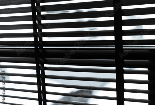 Opened venetian plastic blinds in black and white. Plastic window with blinds. Interior design of living room with window horizontal blinds. Window slatted shades made of plastic. Hopeless and despair