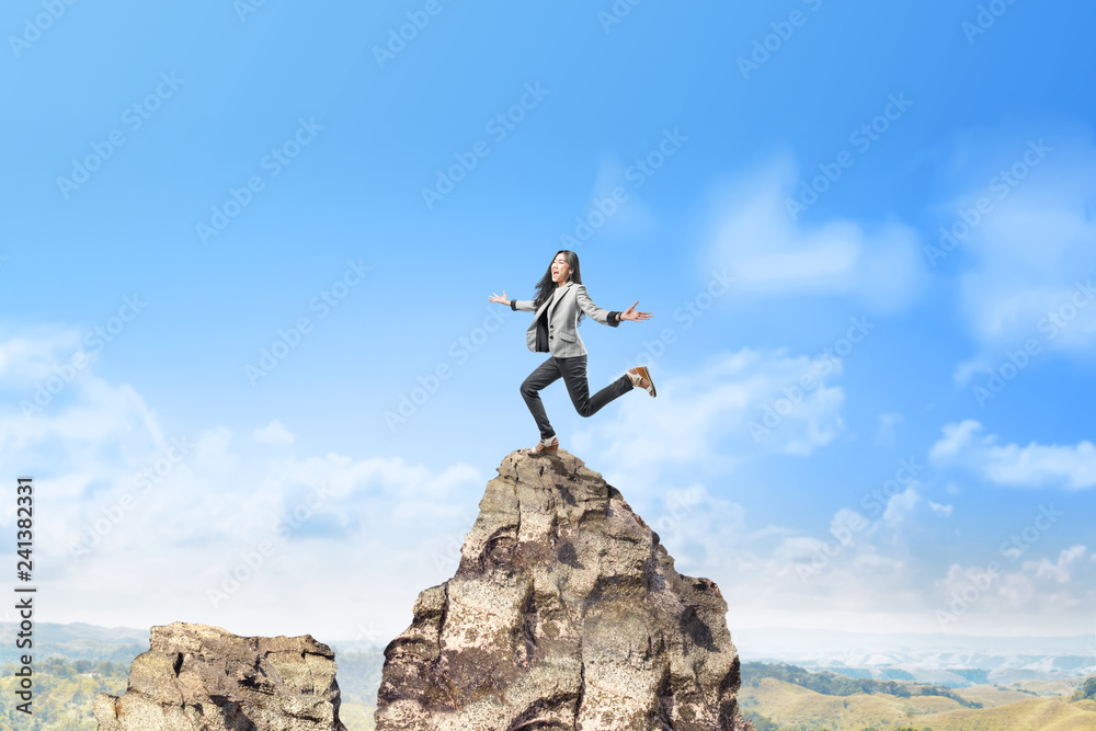 Happy asian business woman jumping on top of the mountain Happy asian business woman jumping on top of the mountain