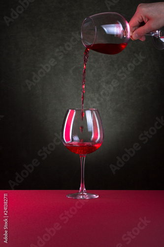 Male hand pouring wine from glass to glass.
