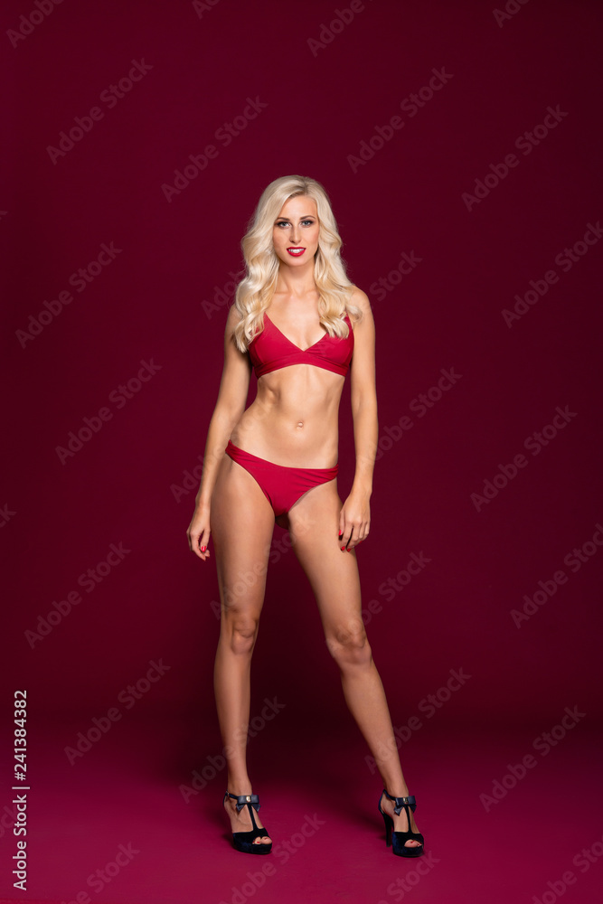 Young and beautiful woman in swimsuit over red background. Young and beautiful woman in swimsuit over red background.