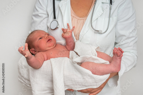 Pediatrician doctor is holding newborn baby in arms