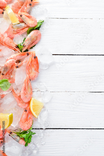 Shrimp with ice and lemon. Seafood. On a white wooden background. Top view. Free copy space.