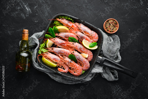 Large grilled shrimp in a frying pan. Tiger prawns. Top view. Free space for your text. On the old background.