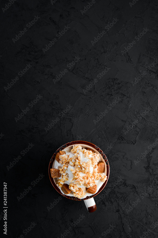 Cappuccino with milk and nuts and marshmallow. On a black stone background. Top view. Free copy space.